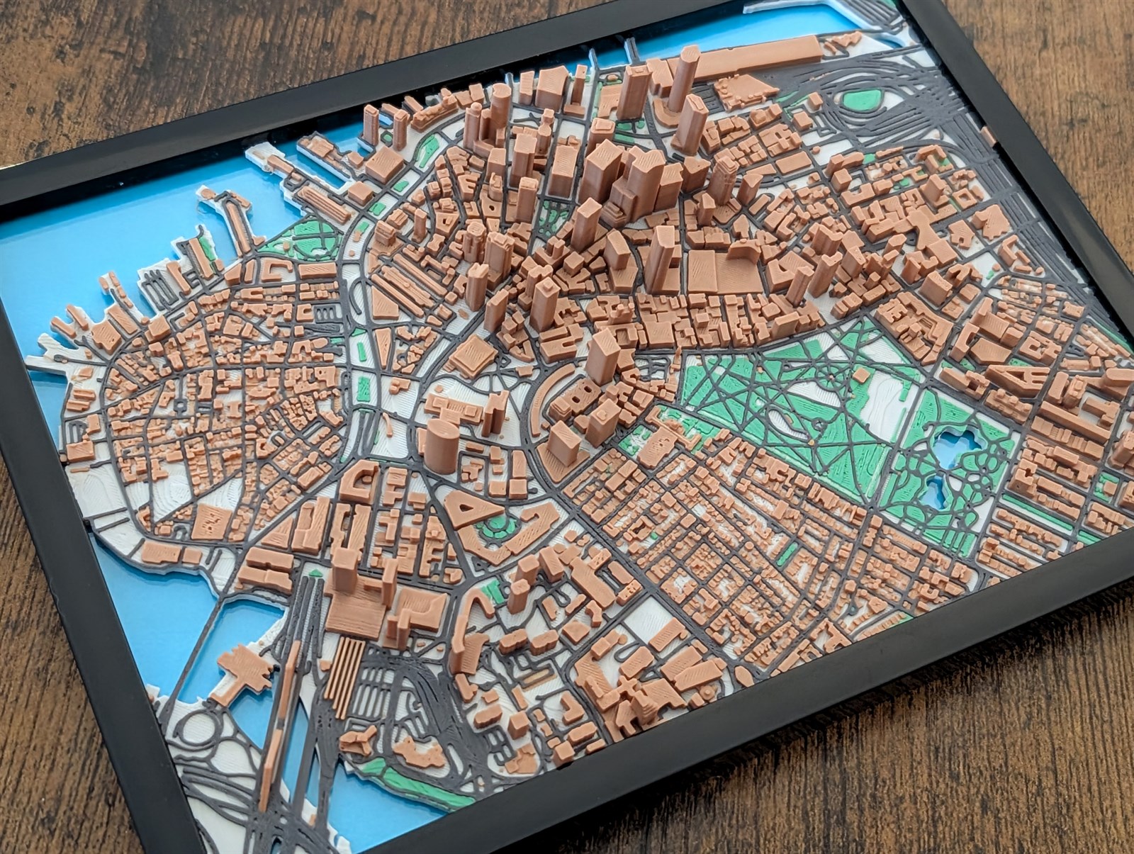Framed 3D print of my manually designed Jarvizar Boston map, with copper-colored buildings, green parks, and blue water